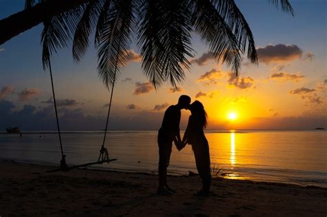 silhueta de casal apaixonado beijos na praia durante o pôr do sol foto premium