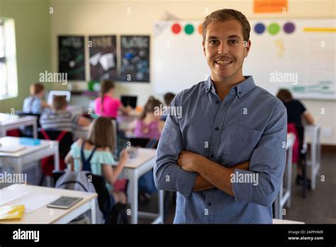 Male School Teacher Standing With Arms Crossed In An Elementary School