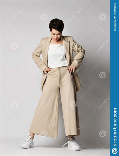 Pretty Short Haired Brunette Woman In Beige Business Smart Casual Suit And Skeakers Standing And