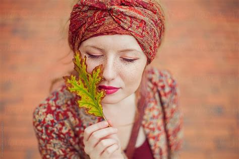 Young Beautiful Woman With Freckles And Closed Eyes Holding A Colourful Lief By Stocksy