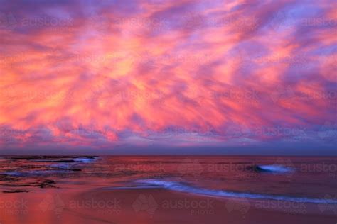 Image Of A Long Exposure Of Dramatic Pink Cloudy Sunset Over The Beach