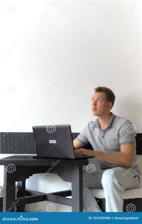 Man Sitting Indoors While Using Laptop Computer While Thinking Stock