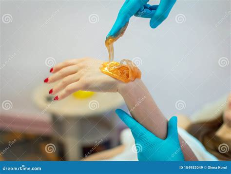 Close Up Hands Of Cosmetologist In Blue Gloves Applying Golden Paste