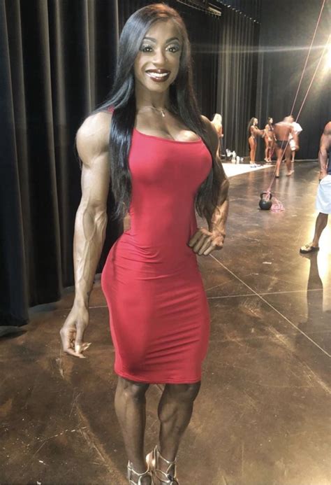 A Woman In A Red Dress Posing For The Camera With Muscles On Her Chest