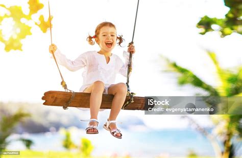 Happy Child Girl Swinging On Swing At Beach In Summer Stock Photo
