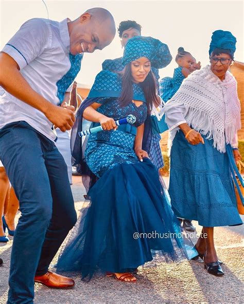 A Group Of People Standing Next To Each Other In Front Of A Woman Wearing A Blue Dress