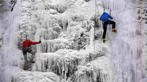 People Climb An Artificial Frozen Waterfall At A Ski Resort In Metabief