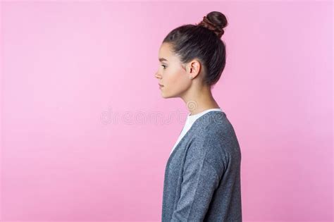 Side View Of Beautiful Brunette Teenage Girl Standing With Serious