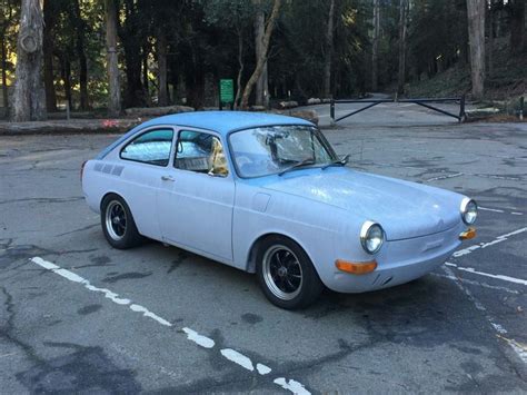 An Old Blue Car Parked In A Parking Lot