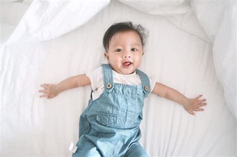 Sonriente niña asiática acostada en una cama Foto Premium