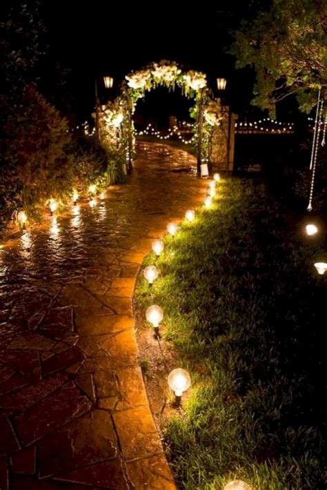 Some Lights Are Lit Up In The Dark On A Path That Is Surrounded By Grass