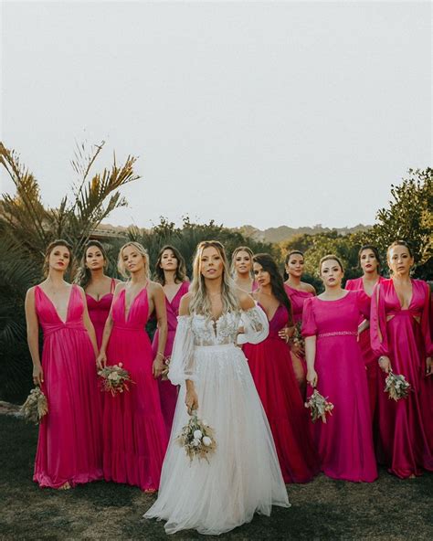 A Group Of Women In Pink Dresses Standing Next To Each Other