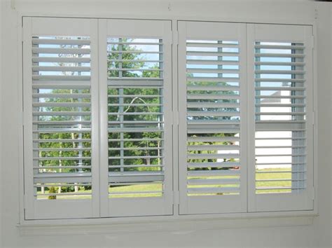 Windows covered with stacked plantation shutters are positioned above a roll top freestanding bathtub fitted with a teak tray and a polished nickel floor mount tub filler and placed on gray marble floor tiles beneath a bell jar lantern. Plantation Shutters - Traditional - Bathroom - boston - by ...