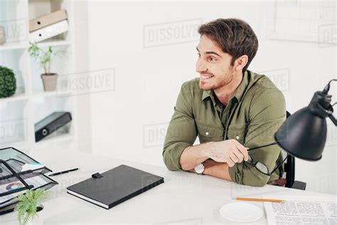 Handsome Office Manager Sitting At Desk With Notebook And Papers