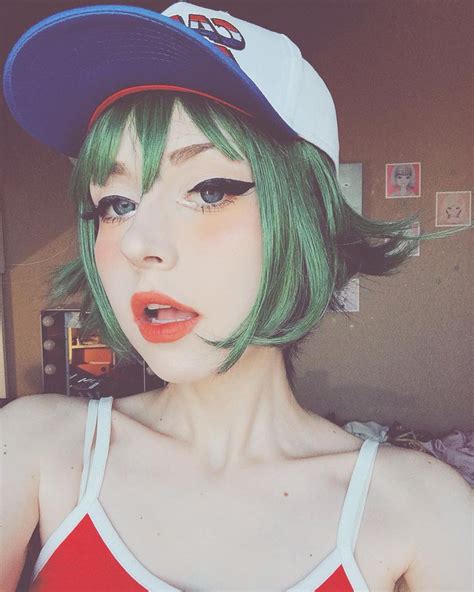 a woman with green hair wearing a baseball cap and red tank top is posing for the camera