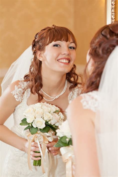 A Beautyful Bride Looks Down At Her Bouquet From Roses Stock Photo