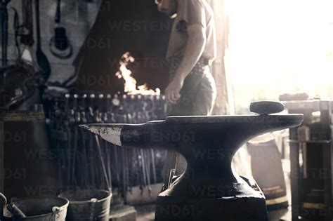 Blacksmith At Fire Behind Anvil In Forge Stock Photo