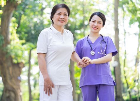 Premium Photo Asian Female Nurse Taking Care Of A Middleaged Female Patient In The Park