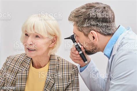 Ent Doctor Checking Elderly Female Ear Using An Otoscope Hearing Exam