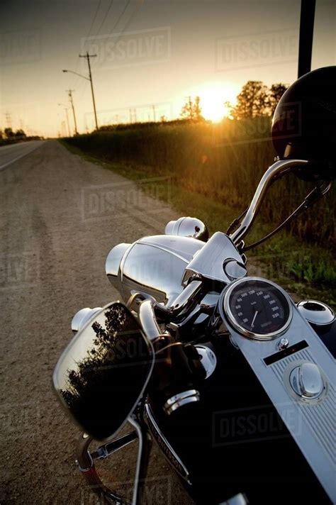 Motorcycle Parked On The Side Of The Road At Sunset Stock Photo