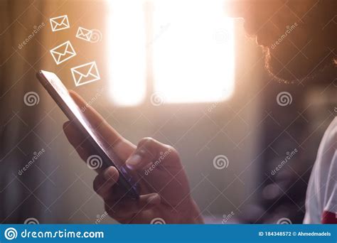 Man Holding Smart Phone In House With Mail Icons Hovering Over The