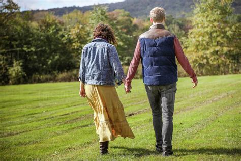 Rear View Of Couple Holding Hands While Walking In A Field Stock