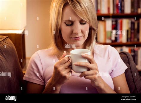 Woman Drinking From Mug On Sofa At Home Stock Photo Alamy