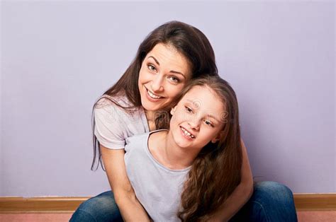 Happy Smiling Emotion Mother Cuddling Her Cute Daughter Sitting On The Floor With Love On Purple