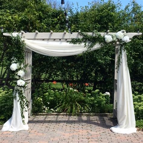 White Fabric And Greenery On A Wooden Wedding Arbor Wedding Pergola
