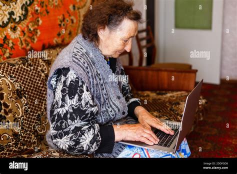 Old Woman Working On Laptop Computer At Home Grandma Using Notebook