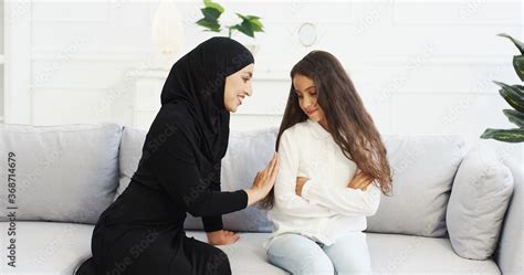 Pretty Smiled Arabian Mother In Black Hijab Talking With Small Teen Daughter And Calming Her