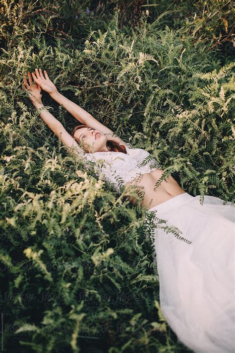 beautiful teen girl in summer white dress lying on the grass by stocksy contributor sergey