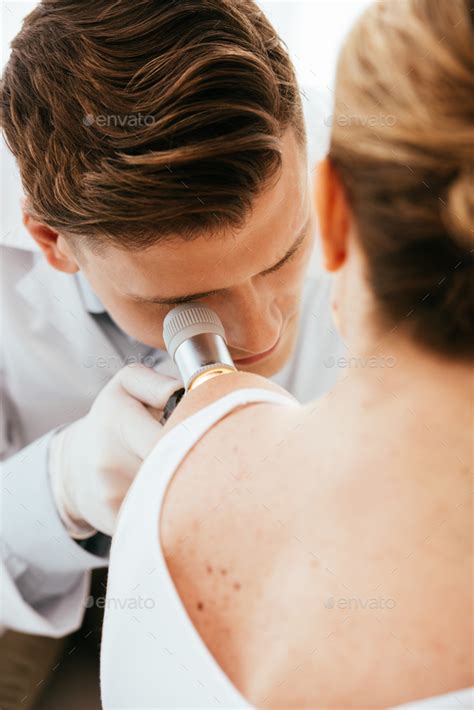 Dermatologist Holding Dermatoscope While Examining Patient With Skin