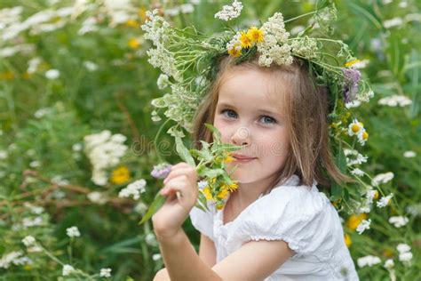 Little Girl Sniffs Wildflowers On A Meadow Stock Photo Image Of