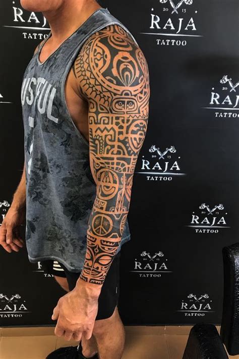 A Man Standing In Front Of A Wall With Tattoos On His Arms