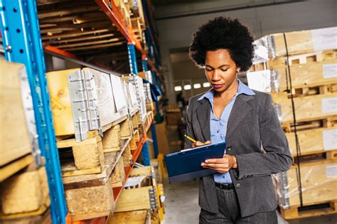 Supervisor Standing Inside Warehouse With Packages And Writing On