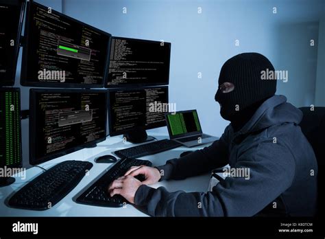 Male Hacker Using Computers With Multiple Monitors To Hack Stock Photo