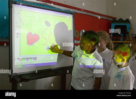 Group Of School Children Using Interactive Whiteboard In Classroom