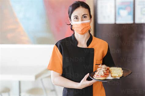 Waitress Serving Food In Cafeteria During Pandemic Stock Photo