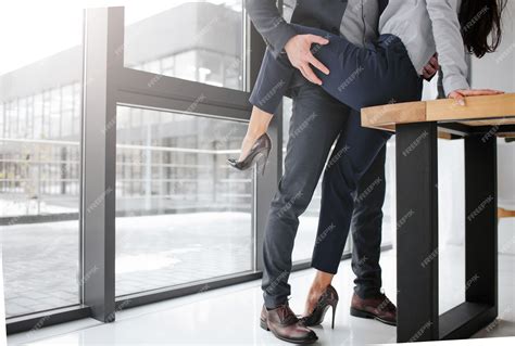 premium photo cut view of man in suit stand and hold woman s leg in sexual pose she sit on table