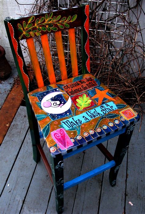 A Painted Chair Sitting On Top Of A Wooden Floor Next To A Plant And Fence
