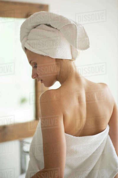 Young Slim Woman Wrapped In White Towel After Taking A Shower Standing Infront Of Mirror Stock