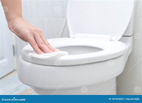 Young Woman Cleaning Toilet Seat By A Wet Wipe In Public Restroom Stock
