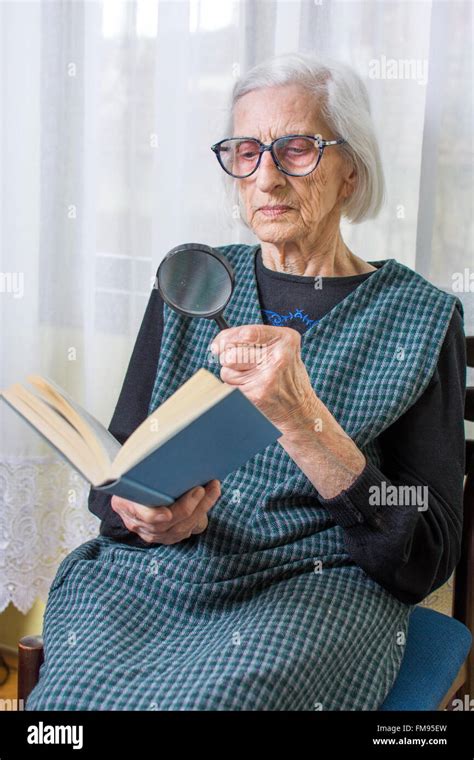 años abuela leyendo un libro a través de una lupa Fotografía de stock Alamy