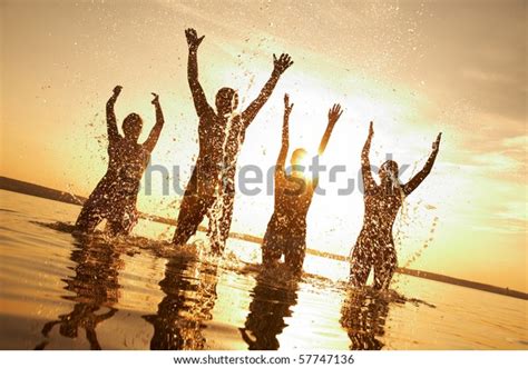 Group Of Happy Young People Dancing And Spraying At The Beach On