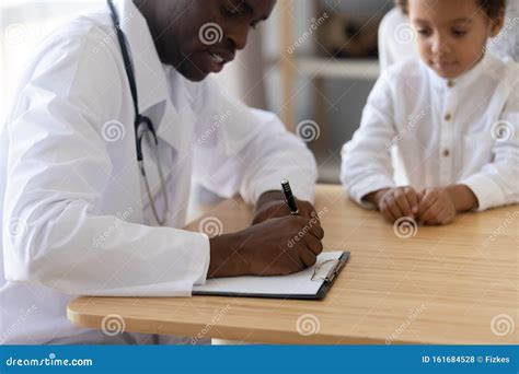 African American Doctor Write Prescription To Child Patient Stock Photo