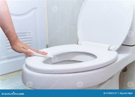 Hand Cleaning Toilet Seat By A Wet Wipe With Alcohol Spray In Public