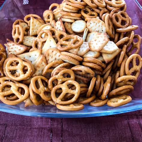 Mix Of Salty Snacks Crackers And Pretzels In Glass Bowl On Purple