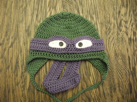 A Crocheted Hat With Eyes And A Scarf