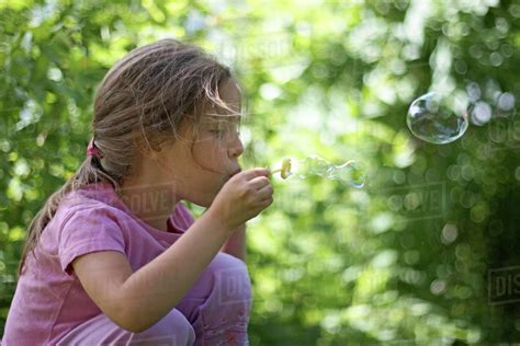 Girl Blowing Bubbles - Stock Photo - Dissolve